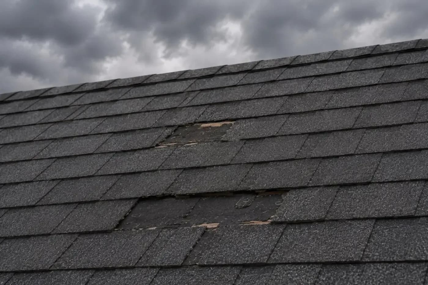Charlotte NC asphalt shingle roof with missing and wind-lifted shingles after a storm