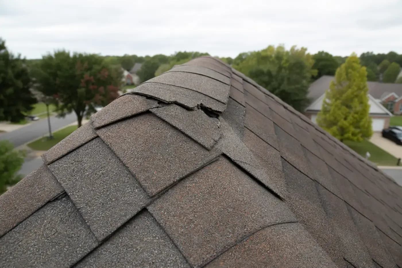 Damaged ridge cap shingles on a Charlotte NC asphalt shingle roof after wind exposure